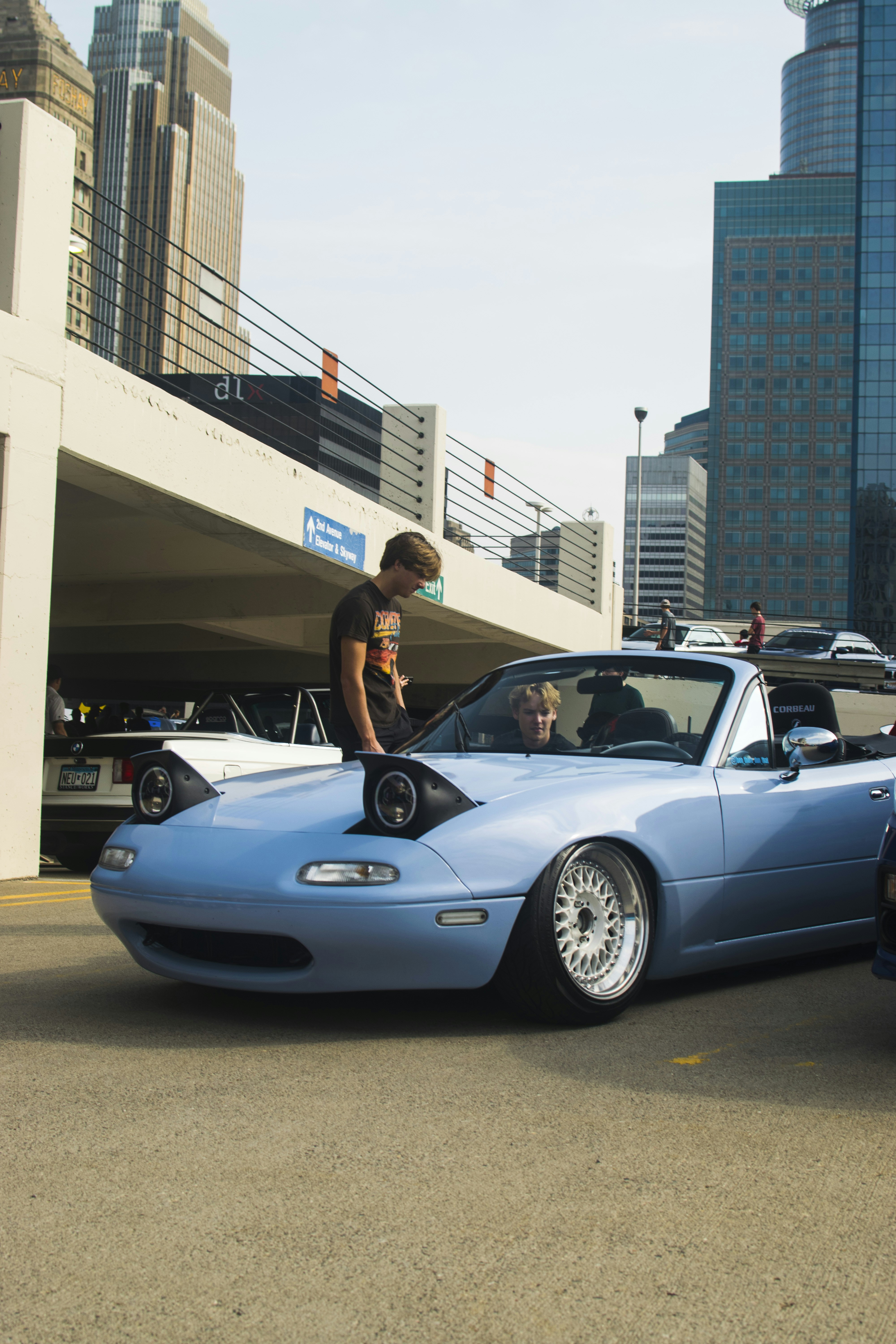 a man standing on the hood of a blue sports car