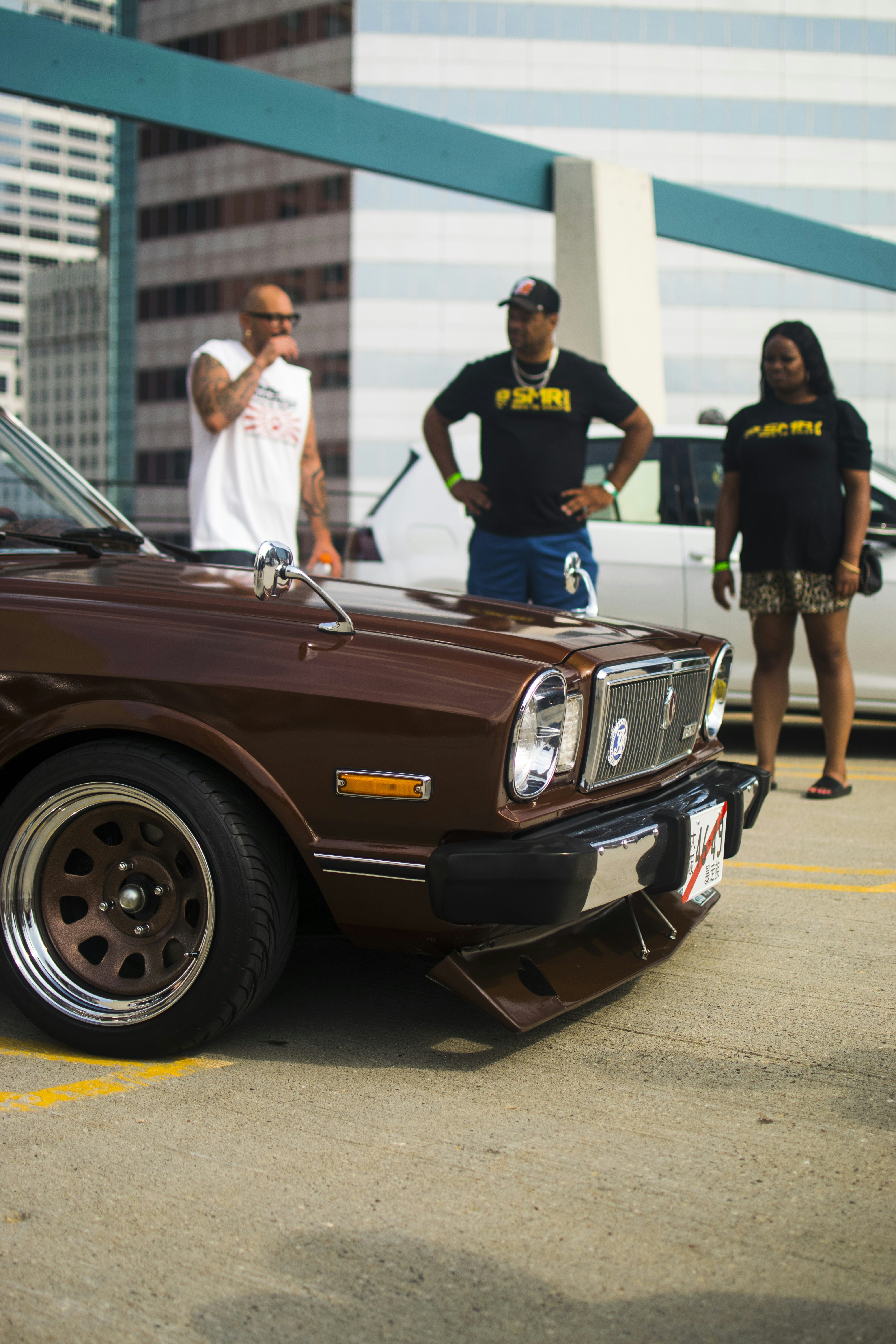 a group of people standing around a brown car