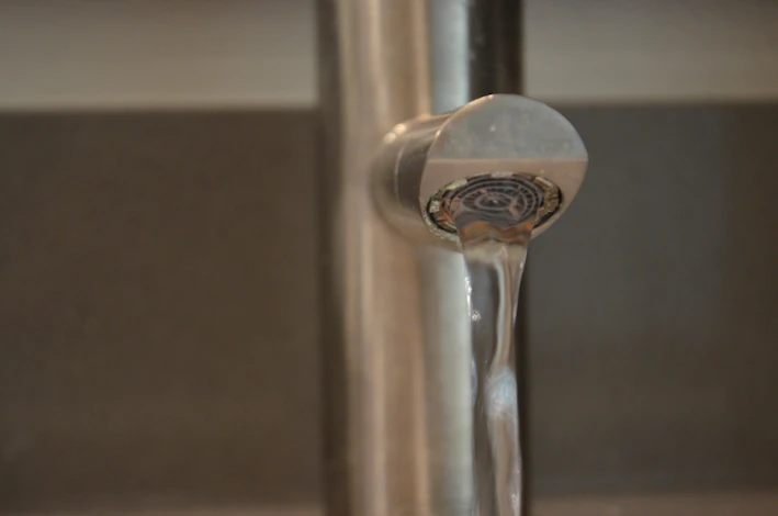 Close-up of a sleek chrome bathroom faucet with water flowing gently