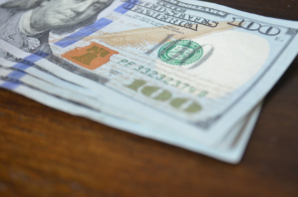 a stack of twenty dollar bills sitting on top of a wooden table