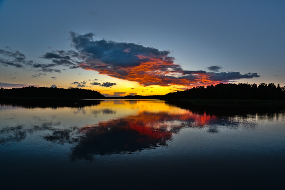 a beautiful sunset over a lake with trees in the background