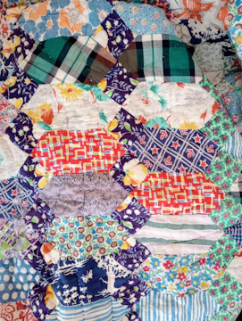 Close-up of assorted quilt blocks laid out on a table, showcasing different fabrics and intricate stitching.