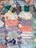 A patchwork quilt featuring an assortment of colorful, patterned fabric pieces. The patterns include floral designs, checkered stripes, and polka dots in various shades including blues, reds, oranges, and greens. The quilt appears to be handmade with intricate stitching connecting the different swatches.