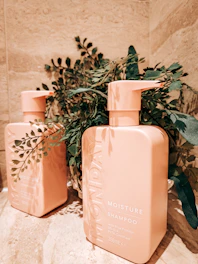 Elegant conditioner bottles with fresh botanical ingredients displayed on a marble countertop.