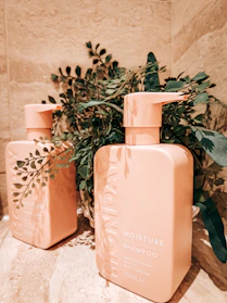 Elegant conditioner bottles with fresh botanical ingredients displayed on a marble countertop.