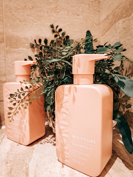 Close-up of vibrant shampoo and conditioner bottles with fresh flowers around