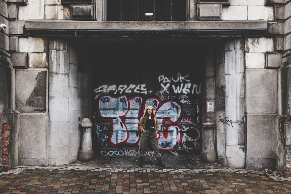 a woman standing in front of a graffiti covered building