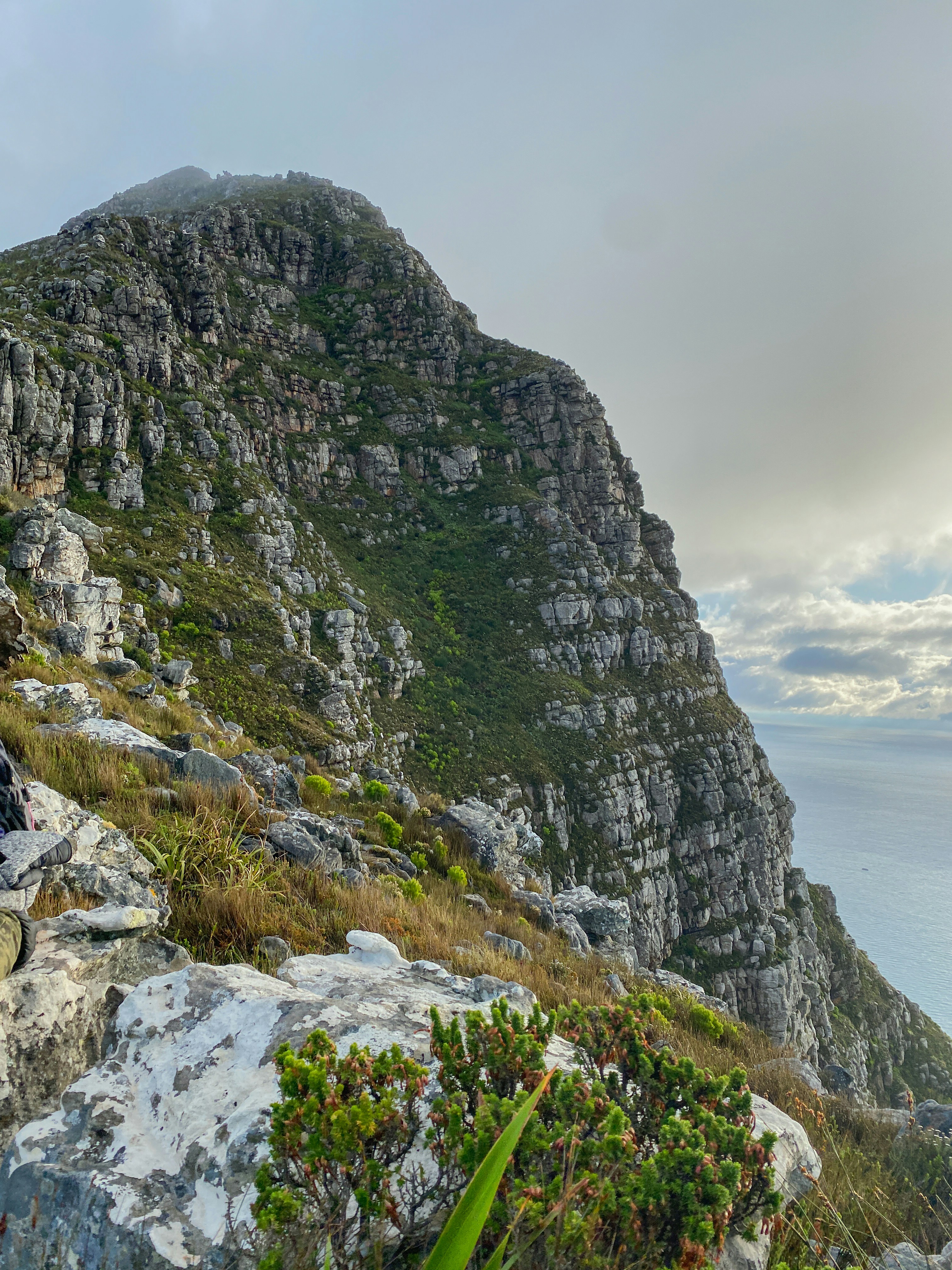Un homme assis au sommet d’une montagne à côté d’un plan d’eau