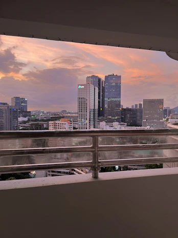 City skyline view from a modern apartment balcony during sunset.