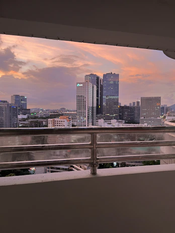 Balcony view overlooking the vibrant Kuala Lumpur cityscape at sunset.