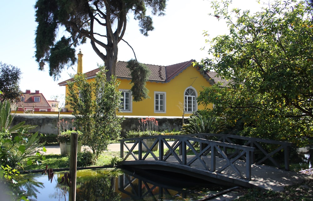 a yellow house with a bridge over a pond