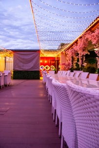 Elegant outdoor dining set with a large table and comfortable chairs under string lights.