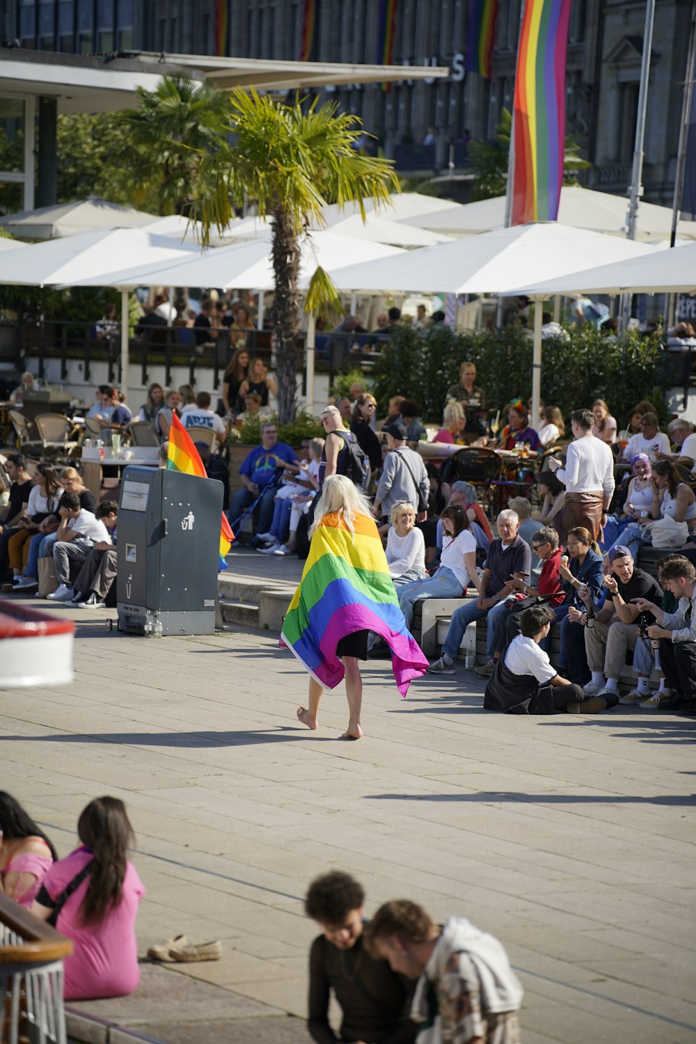 a woman in a colorful dress holding a rainbow flag