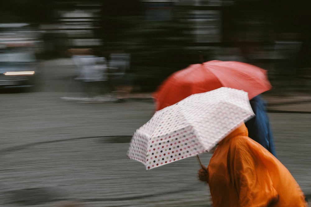 a couple of people walking down a street holding umbrellas