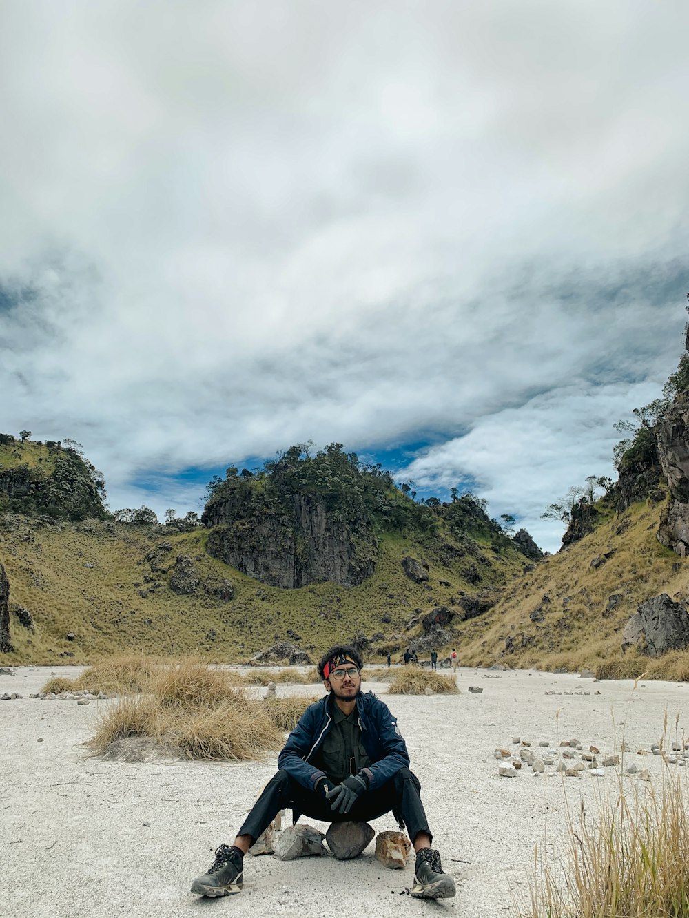 a man sitting on the ground in the middle of nowhere