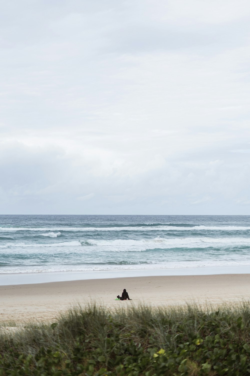 a couple of people sitting on top of a sandy beach