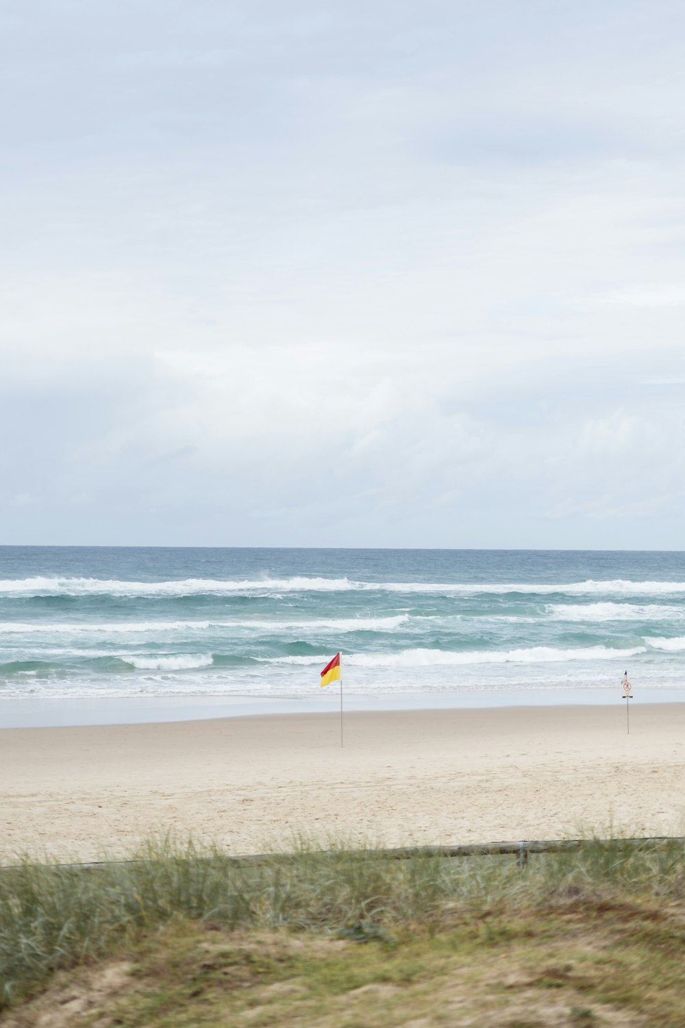 a flag on a beach next to the ocean