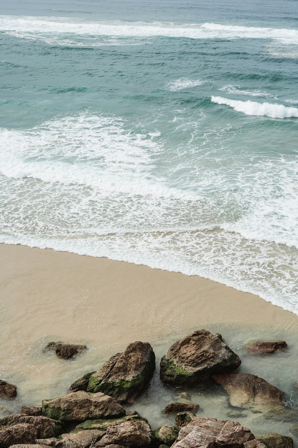 a couple of rocks sitting on top of a sandy beach