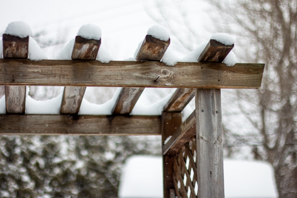 a wooden pergol with snow on top of it