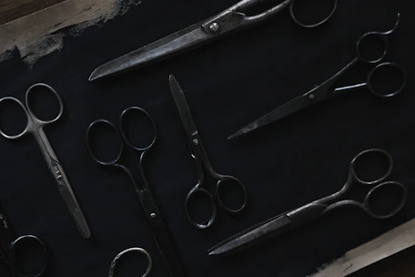 Industrial scissors resting on a dark charcoal surface with metallic silver accents.