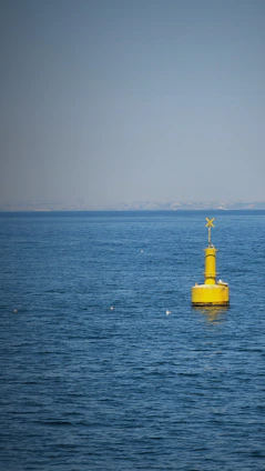 A calm sea with a bright buoy floating steadily, symbolizing resilience and steady progress.