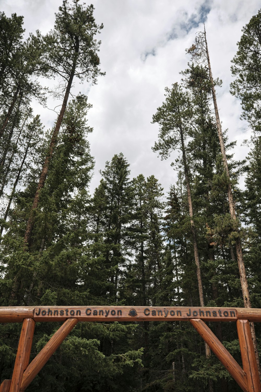 a wooden bridge with a sign on it in the middle of a forest