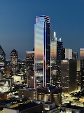 A sleek LED screen glowing brightly on a modern city building at dusk.