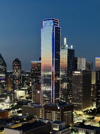 A sleek LED screen glowing brightly on a modern city building at dusk.