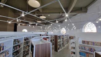 A modern library space filled with Arabic books and digital resources.