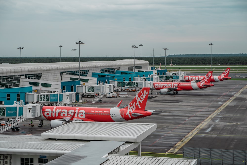 a row of red and white airplanes parked at an airport