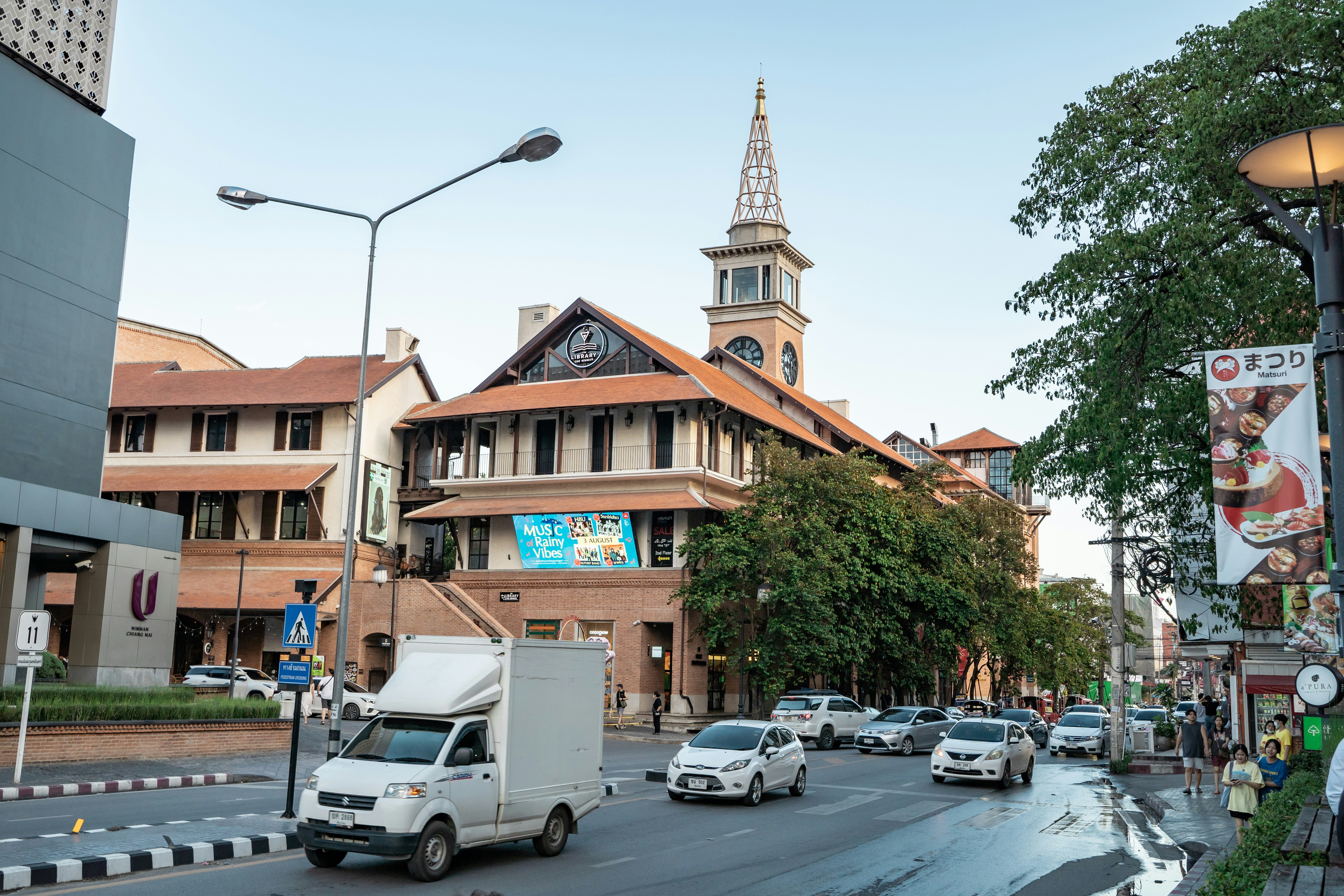 a busy city street with a church steeple in the background