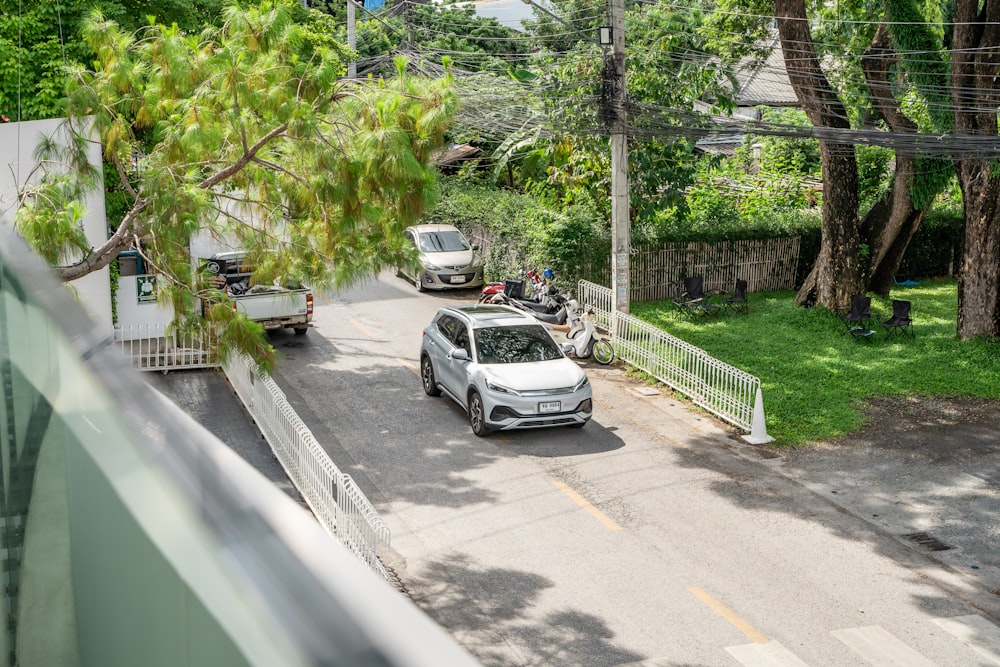 a white car driving down a street next to a lush green park