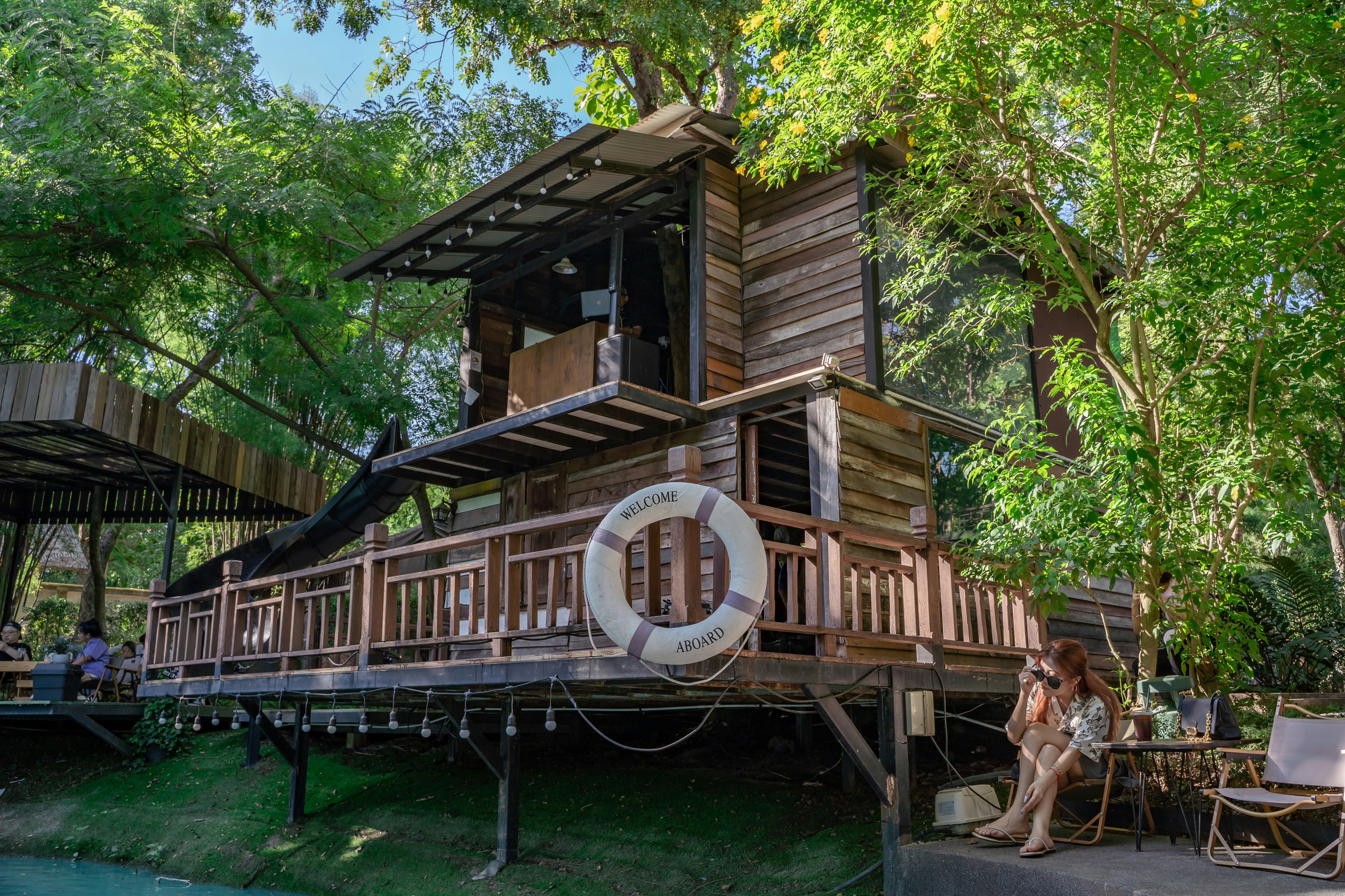 a woman sitting on a deck in front of a tree house