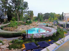 Outdoor swimming pool surrounded by lush greenery and sun loungers on a sunny day.