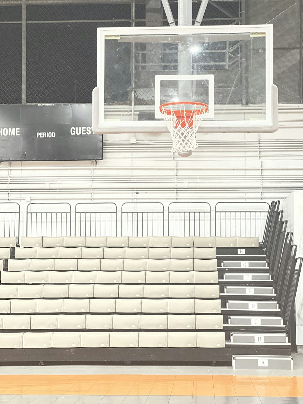 a basketball hoop in a gym with empty bleachers