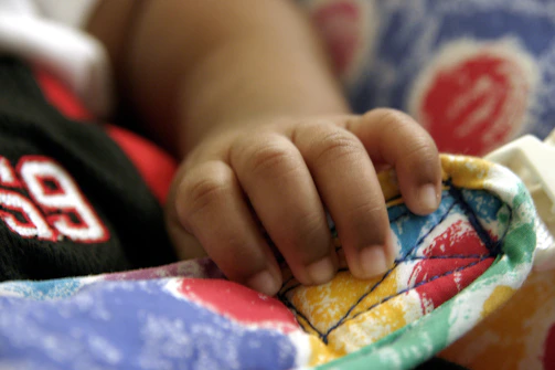 Close-up of a hand holding a bright, patterned t-shirt with playful designs.