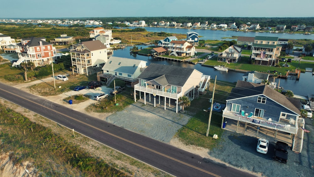 an aerial view of a street with houses and a body of water in the background