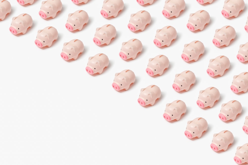 흰색 표면에 작은 분홍색 돼지 인형 그룹
