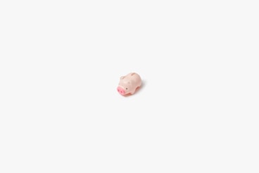 a small pink pig sitting on top of a white surface