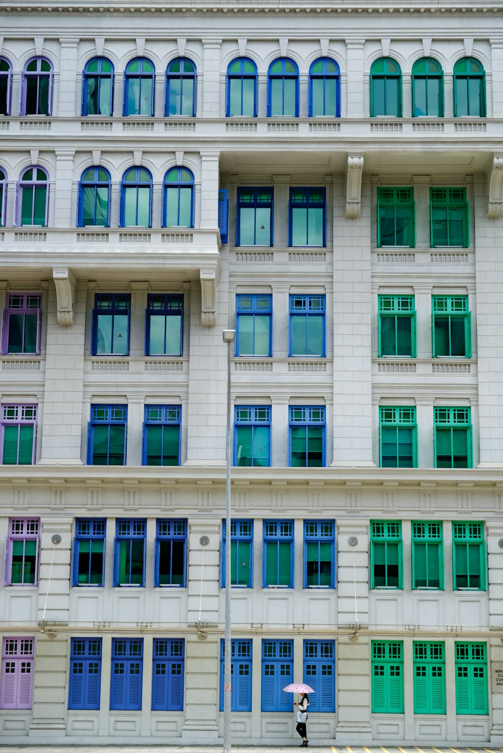 a person with an umbrella walking past a building