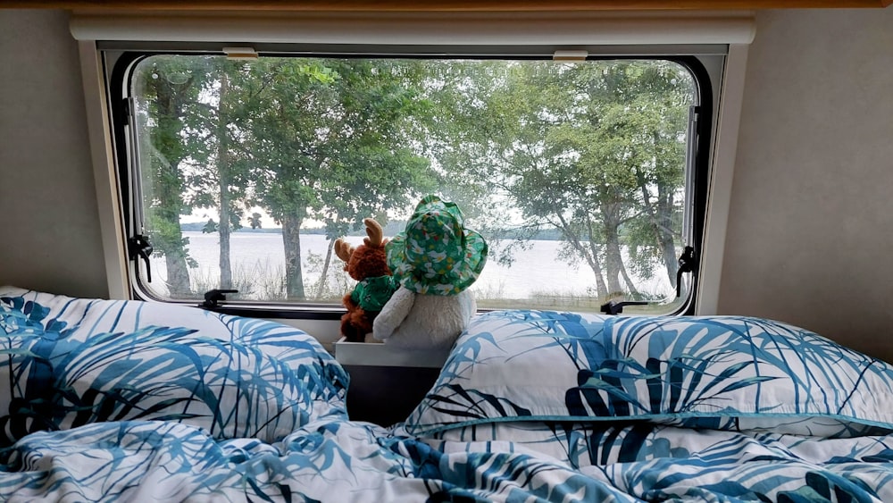 a teddy bear sitting in a window seat of a camper