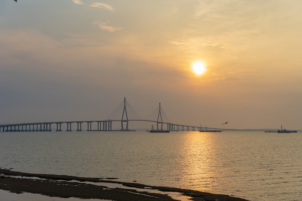 the sun is setting over a large bridge