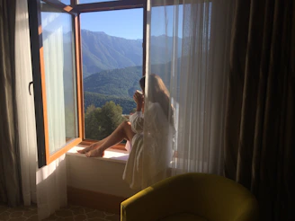 A guest enjoying a serene moment looking out a large window with scenic views.