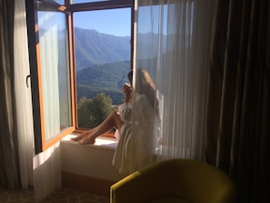 A peaceful mountain backdrop visible through a window where a mother rests.