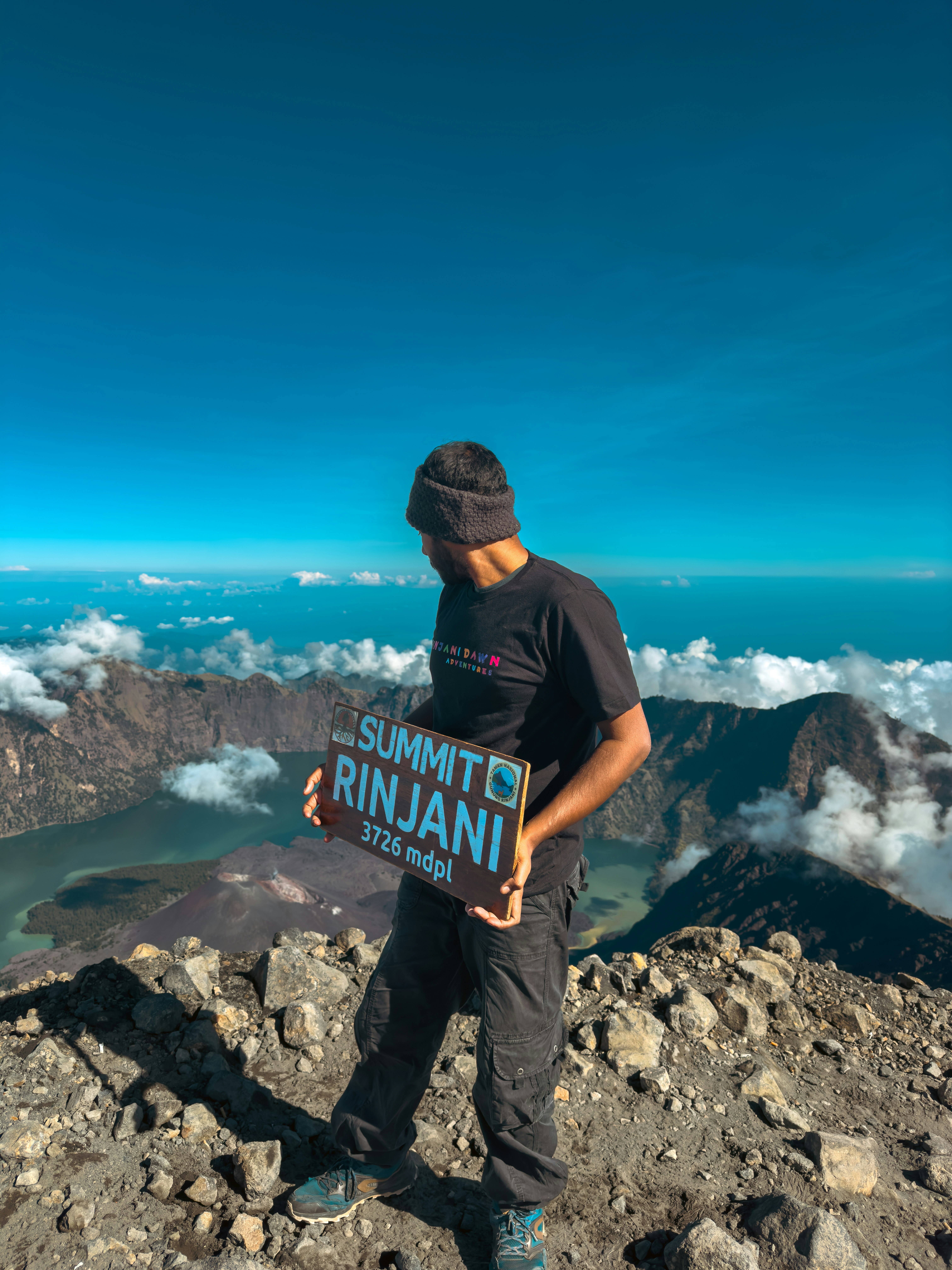 Seorang pria berdiri di atas gunung memegang tanda
