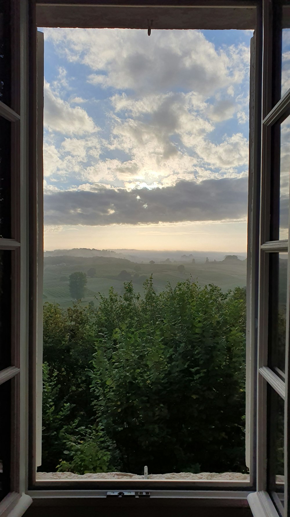 an open window with a view of the countryside