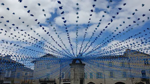 A lively city square decorated with red, white, and blue flags celebrating a local festival.