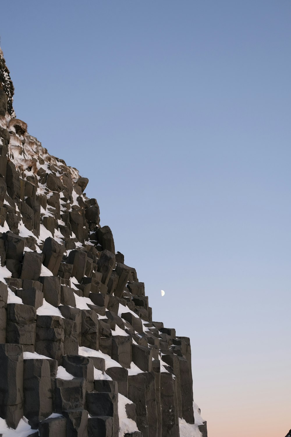 the moon is setting behind a large rock formation