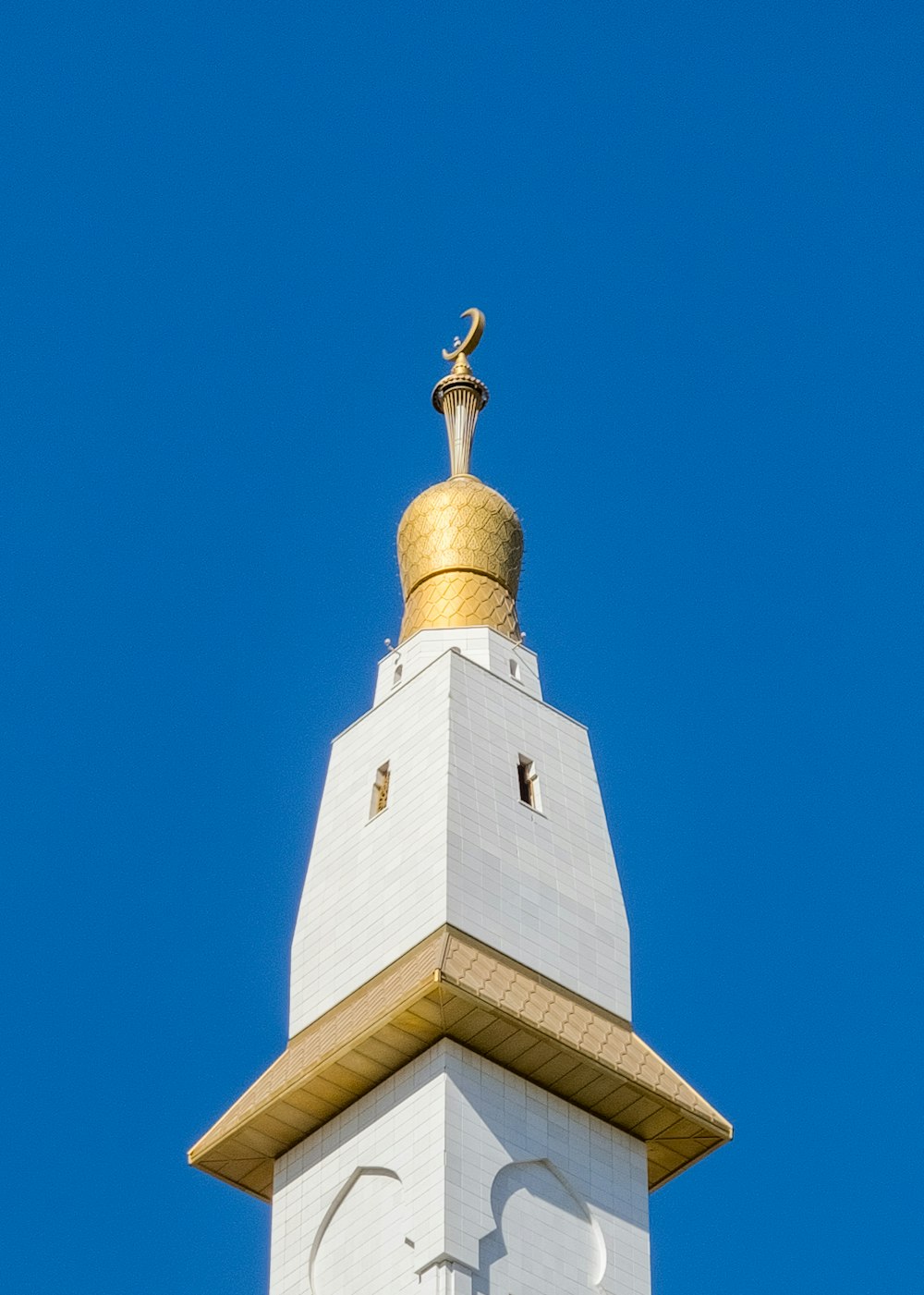 a tall white clock tower with a gold top