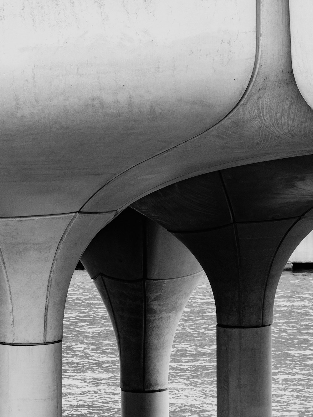 a black and white photo of a bridge over water